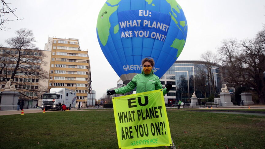 A guy in front of a globe holding a banner promoting green planet