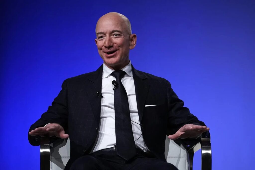 jeff bezos sitting on a chair smiling and saying something